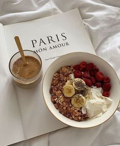 a bowl of granola, yogurt and raspberries next to a book