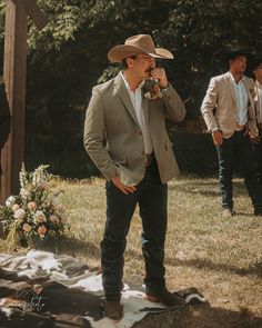 a man in a cowboy hat standing next to another man wearing a suit and tie