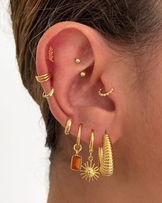 a woman wearing gold ear cuffs and earrings