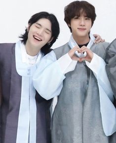 two young men standing next to each other with their hands in the shape of a heart