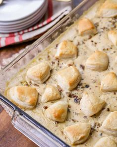 a casserole dish filled with biscuits and sauce on top of a wooden table