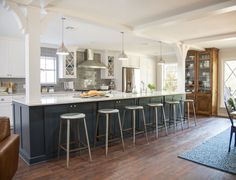 a kitchen with an island and bar stools in the center, along with several chairs