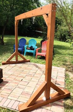 a wooden frame sitting on top of a brick patio next to two lawn chairs and a fire pit