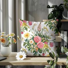 a white vase filled with flowers sitting on top of a table next to a pillow