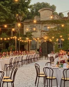 an outdoor dining area with tables and chairs set up for a formal dinner in front of a large building