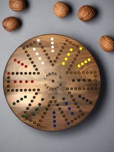 a wooden board with several different colored dots on it and nuts scattered around the board