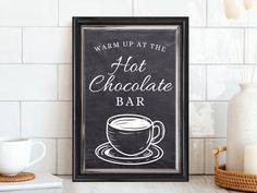 a chalkboard sign that says warm up at the hot chocolate bar next to a cup of coffee