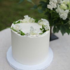 A tall round cake frosted with smooth white buttercream and decorated with a white floral crown. Small Minimalist Wedding Cake, Small One Tier Wedding Cake, Frosting Styles, Tiny Wedding Cake, Individual Wedding Cakes, Wedding Cake Gift, Single Layer Cakes, Raspberry Buttercream, Rainbow Carrots