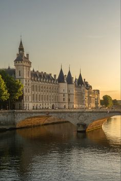 an old castle is next to the water with a stone bridge in front of it