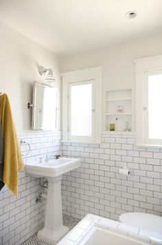 a bathroom with white brick walls and flooring is pictured in this image, there are towels hanging on the rack next to the bathtub