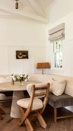 a dining room table with two chairs and a bench in front of it, next to a window