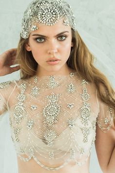 a woman wearing a bridal veil and headpiece with beads on her hair is posing for the camera