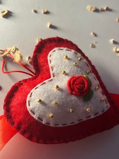 a red and white heart shaped ornament with a rose on it's side