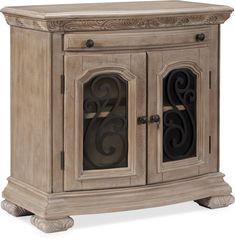 an antique style cabinet with glass doors and carvings on the front, in light wood