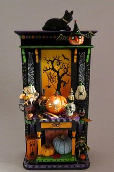 a black cat sitting on top of a halloween cabinet