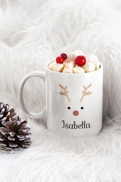 a mug with marshmallows in it and a pine cone on the side