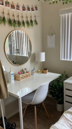 a white desk with a mirror on the wall above it and plants hanging from the ceiling