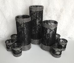 a group of black vases sitting next to each other on a white tablecloth