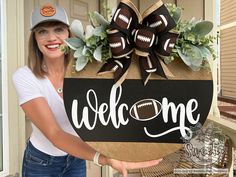 a woman holding up a welcome sign with footballs on it