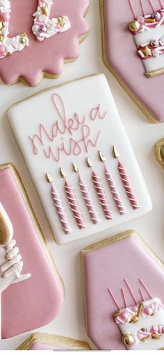 pink and white cookies decorated with icing on top of each other in the shape of letters