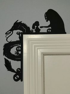 a black silhouette of a gorilla and monkey on a white door frame next to a gray wall