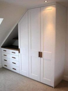 an attic bedroom with white cabinets and drawers