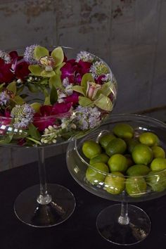 two glass bowls with flowers and limes in them