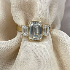 an emerald cut diamond ring on top of a white cloth