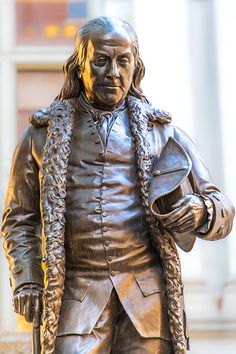 a statue of a man holding a cane in front of a building