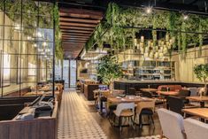 the interior of a restaurant with plants hanging from the ceiling and tables in front of it