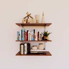 two wooden shelves with books and vases on them, against a white wall background