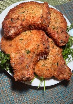 three pieces of fried chicken on a white plate with green garnishes and parsley