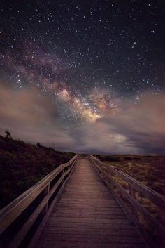 a wooden walkway leading to the stars in the sky