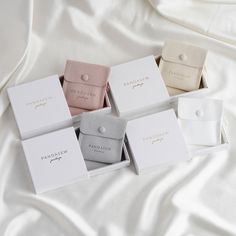 five small boxes with rings on them sitting on a white cloth covered bedding area