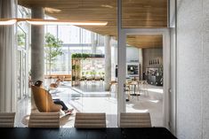 a person sitting on a chair in the middle of a room with glass doors and windows