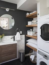 a washer and dryer in a small room with black walls, white tile flooring and wooden shelves