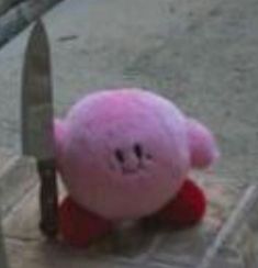 a pink teddy bear with a knife stuck in it's back end sitting on the ground