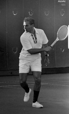 a man holding a tennis racquet on top of a hard surface tennis court