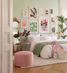 a bedroom decorated in pastel green and white with pictures on the wall above the bed