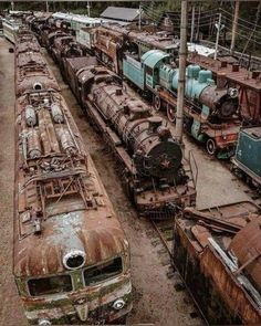 an old train yard with rusted cars and trains