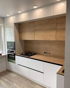 an empty kitchen with white cabinets and wooden counter tops, along with a stove top oven