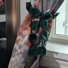 a curtain with crocheted flowers hanging from it's side in front of a window