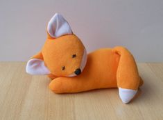 an orange stuffed animal laying on top of a wooden table