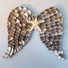 two angel wings made out of shells on a wall