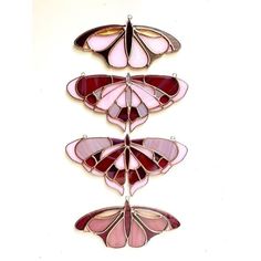 three pink and red stained glass butterflies on a white background