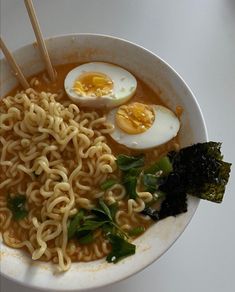 a bowl filled with noodles, eggs and greens