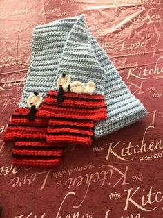 a pile of crocheted towels sitting on top of a bed next to a red blanket