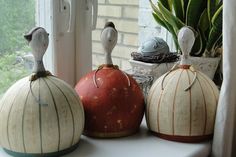 three ceramic birds perched on top of each other in front of a window sill