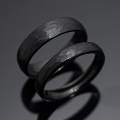 two wedding rings sitting next to each other on top of a gray surface with shadows