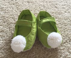 a pair of green shoes with white pom - poms